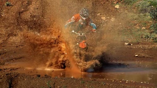 Motocross Rider Splashing Through Mud Puddle