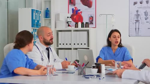 Team of Doctors During Brainstorming Sitting at Desk in Meeting Medical Office