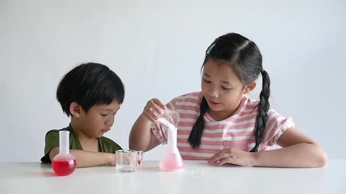 Brother and Sister Performing Science Experiment at Home