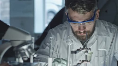 Scientist Working in Lab with Microscope and Test Tubes