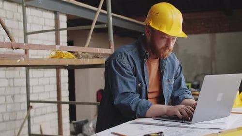 Construction Worker Using Laptop On Building Site