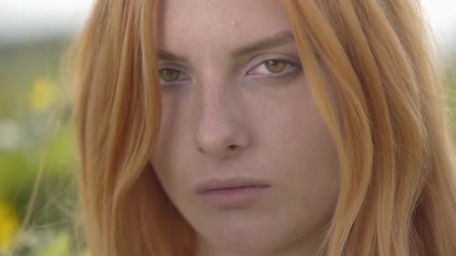 Close-up Face of Young Confident Girl with Red Hair and Green Eyes Looking at the Camera Outdoors