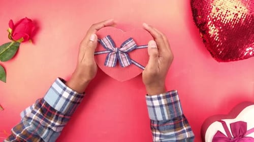 Top View of Man's Hand Holding a Gift Box on Red Backgrund