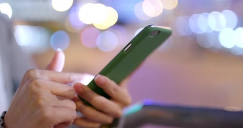 Hands Using Smartphone at Night with Bokeh Background