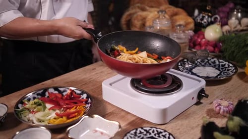 Chef Cooks Vegetables and Noodles in Frying Pan