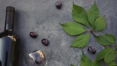 Top View of Bottle of Red Wine Green Vine Wineglass and Ripe Grape on Vintage Dark Stone Table