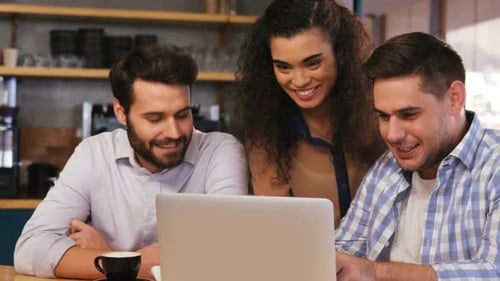Colleagues Collaborating Around a Laptop in a Coffee Shop
