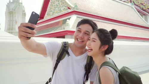 Couple using mobile phone selfie photo view while spending sweet time in holiday trip in sunset.