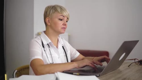 Woman Doctor Typing on Laptop at Desk