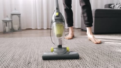 Person Vacuuming Rug in Brightly Lit Home