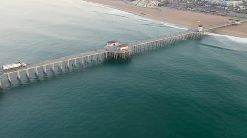 4k ariel drone shot of the pier in Huntington Beach, Surf City USA, California as surfers catch wave
