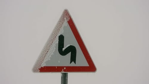 Highway Sign of Mountain Winding Road in Heavy Snowfall Weather