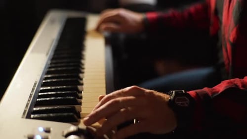 Hands Playing Keyboard in Dark Studio Setting