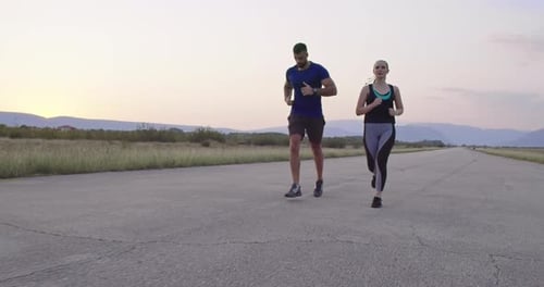 Tracking Slow Motion Shot of Sportive Couple Jogging Outdoors in the Morning Trail Running
