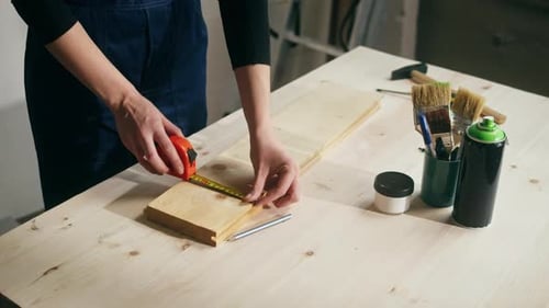 Woman Builder Using Roulette Wheel and Drawing Mark on Wooden Board Closeup