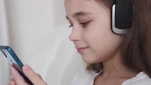 Girl Wearing Headphones Using a Phone Indoors