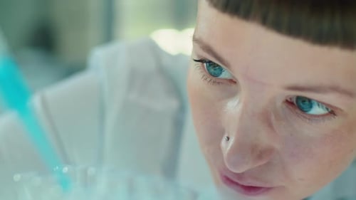 Woman Scientist Pipetting Blue Liquid into Test Tubes