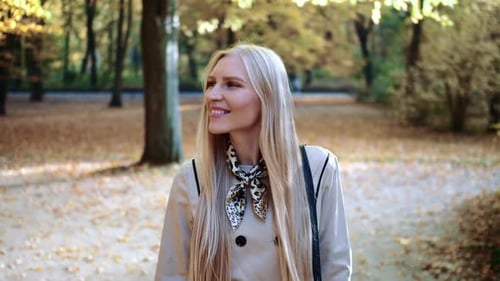 Beautiful Young Blonde Girl Walking in the Park in Autumn