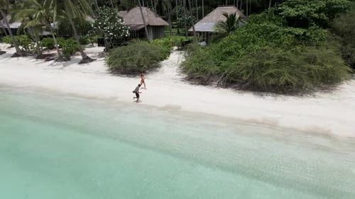 An Aerial View of a Happy Couple Running on Beach