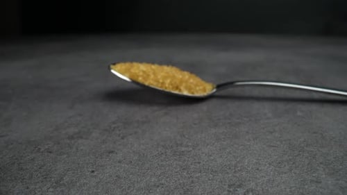 Spoonful of Golden Brown Sugar on Dark Gray