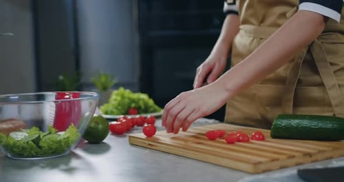 Person Slicing Tomatoes for Salad Preparation
