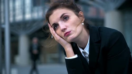 sad and stressed businesswoman sitting in the street