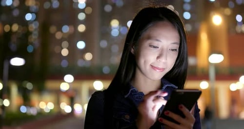 Woman use of mobile phone in city at night