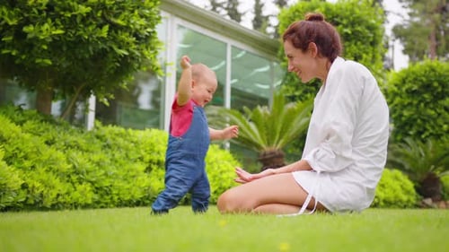 Smiling Baby Walks to Cheering Adult in Garden
