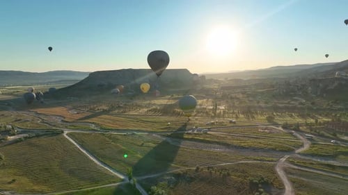 Hot air balloons fly over the mountainous landscape of Cappadocia, Turkey.