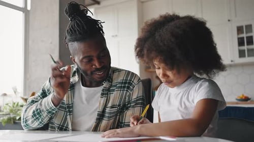 Cheerful African American Father and Daughter Spending Time Together at Home Drawing and Talking at