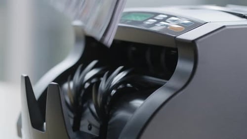 Primer plano de una máquina contadora de dinero con billetes de 100 dólares.