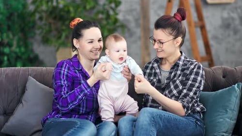 Two Smiling Women with Baby at Home