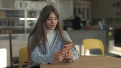 Pretty Caucasian Woman Sitting at Cafe Table with Mobile