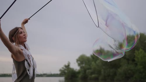 Woman Making Giant Bubbles Near a Lake