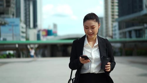 business woman walking and using her smartphone in the city