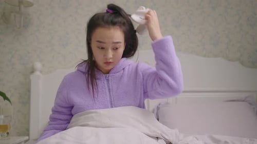 Une femme asiatique des années 20 se réveillant avec un masque de sommeil et regardant un téléphone portable se rendant compte qu'elle est en retard