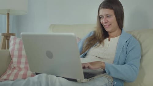 Woman Working on Laptop at Home on Sofa