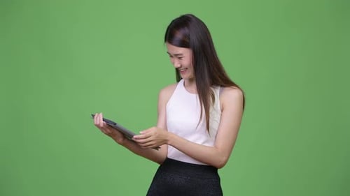 Young Woman Uses Tablet on Green Background