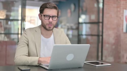 Man Using Laptop Looks Worried in Office