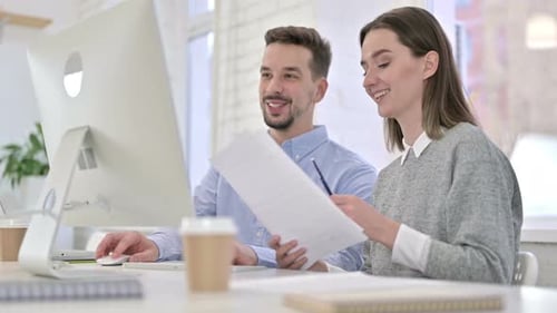 Colleagues Work Together at Desk in Office