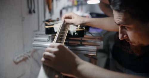 Man Working on Electric Guitar in Workshop