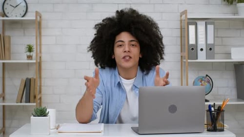 Young Adult with Afro Gestures at Desk