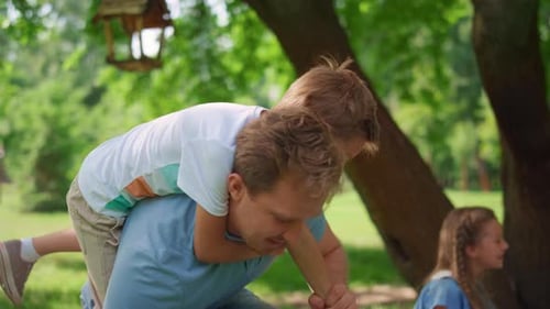 Playful Son Riding on Back Blond Man Closeup