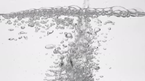Trinkwasser in Glas über Weiß gießen