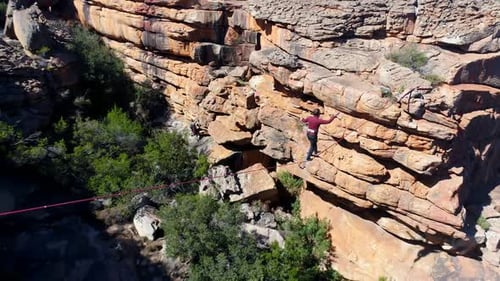 Male highliner walkng on a rope over rocky mountains 4k