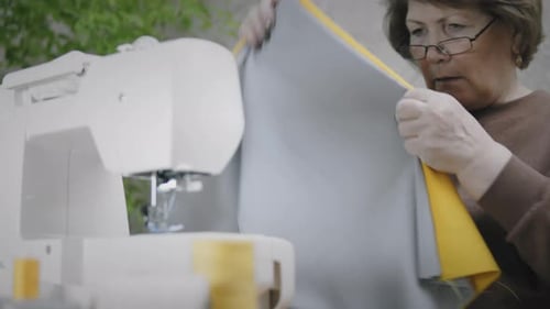 Woman Sewing Gray and Yellow Fabric Indoors