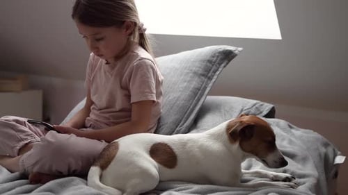 Child Using Phone with Dog Lying on Bed