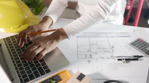 Architekt tippt Tastatur ein, um das Design des Hauses zu überprüfen, bevor die Zeichnung mit dem Lineal auf dem