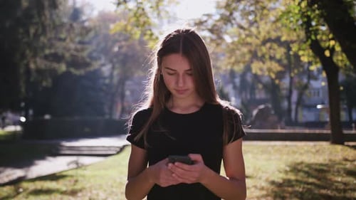 An Attractive Young Lady Using a Phone in Town. Medium Shot