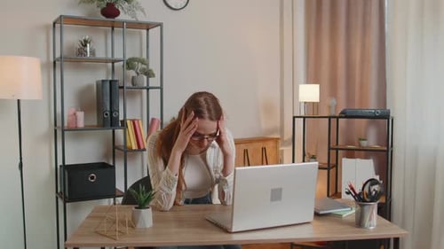 Müde Freiberuflerin mit Laptop-Computer unter Spannungs-Migräne-Kopfschmerzen im Heimbüro